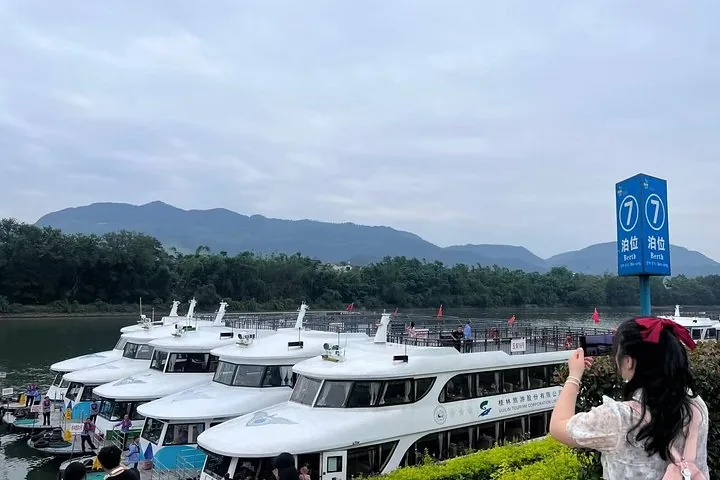 Tourist taking a photo of river cruise boats docked at a pier