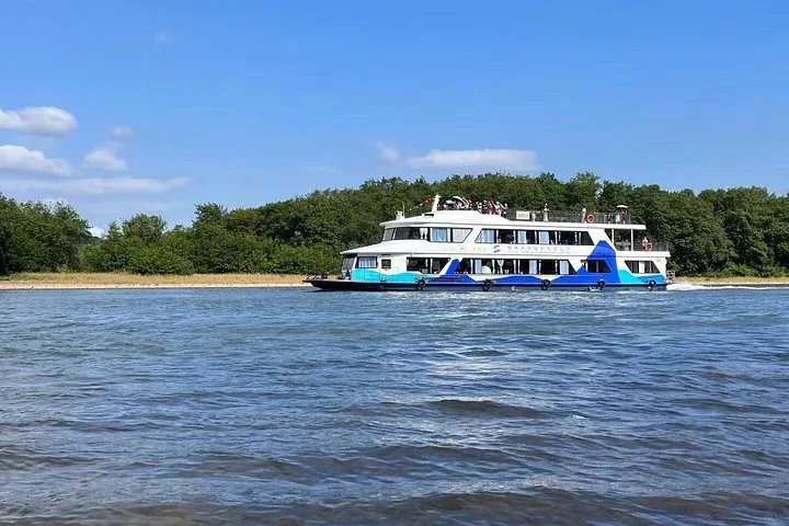 A passenger cruise boat traveling on the Li River with hills behind