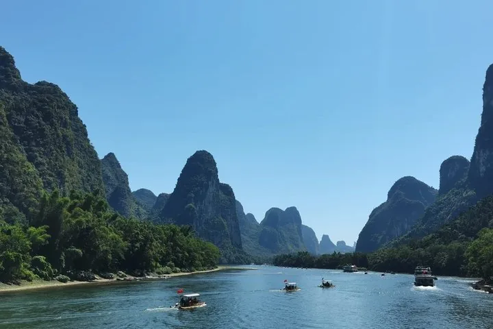 Small boats and cruise ships on the Li River surrounded by dramatic peaks